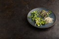 Blue ceramic plate with microgreen sprouts of green pea, sunflower, alfalfa, radish on black. Side view