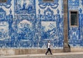 Blue ceramic tiles azulejo on beautiful cathedral wall, and lonely walking man on sunny street