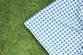 Blue checkered picnic cloth on green grass top view. Checkered towel country design backdrop. Food advertisement display Royalty Free Stock Photo