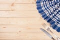 Blue checkered tablecloth with knife and fork on a light wooden table with copy space for your text. Top view Royalty Free Stock Photo