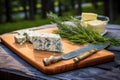 blue cheese on cedar plank with grill tools nearby