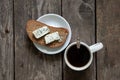 Blue cheese on a piece of black bread and a cup of coffee on an old wooden table Royalty Free Stock Photo