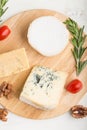 Blue cheese and various types of cheese with rosemary and tomatoes on wooden board on a white background . Top view Royalty Free Stock Photo