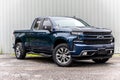 Blue Chevrolet Silverado pickup truck parked in a lush green grassy field.