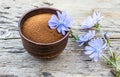 Blue chicory flower and a bowl of instant chicory powder on an old wooden table. Chicory powder. The concept of healthy eating a Royalty Free Stock Photo