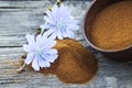 Blue chicory flower and a bowl of instant chicory powder on an old wooden table. Chicory powder. The concept of healthy eating a Royalty Free Stock Photo