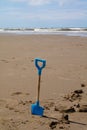 Blue childs spade on the beach with sea in the distance