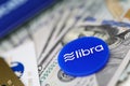 Blue chip with libra sign lying on big pile of US dollars