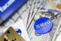 Blue chip with libra sign lying on big pile of US dollars