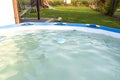 Blue chlorine dispenser floating in a home pool in garden, cleaning and care of the domestic pool.