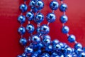 Blue Christmas Beads, Garland on Red. Abstract Background Royalty Free Stock Photo