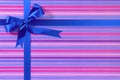 Blue Christmas or birthday gift ribbon bow on candy stripe wrapping paper background Royalty Free Stock Photo