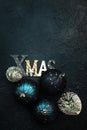 Blue Christmas or New Year background with blue Christmas balls, berries, fir trees, and inscription Xmas, top view