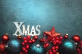 Blue Christmas or New Year background with red and blue Christmas balls, berries, stars and inscription Xmas, top view