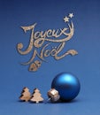 Blue Christmas tree ball with small wooden tree shapes with text Joyeux Noel