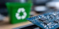 A blue circuit board with several chips and resistors on it, in front of a green recycling bin Royalty Free Stock Photo