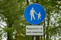 Blue circular shape road sign for pedestrians and cyclists in the city park. Caption below sign: Cycling is allowed. Royalty Free Stock Photo