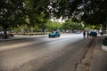 A blue vintage american car driving on an old asphalt road with trees on both sides, Havana, Cuba Royalty Free Stock Photo