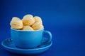 On a blue classic background, a blue cup with macaron horizontal view,