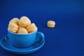 On a blue classic background, a blue cup with macaron horizontal view, soft focus, closeup