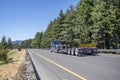 Blue classic big rig semi truck tractor transporting heavy duty step down semi trailer with oversize load sign on the back running Royalty Free Stock Photo