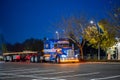 Blue classic big rig semi truck with turned on lights and flat bed semi trailer rest standing on the truck stop parking lot at Royalty Free Stock Photo