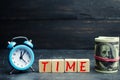 Blue clock, the inscription `time` and money on a black background. The concept of `time - money.` Time management. Saving money