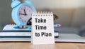 A blue clock sits on a table next to a white planner that says Take time to Plan. Royalty Free Stock Photo