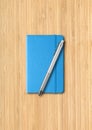 Blue closed notebook with a pen on wooden background