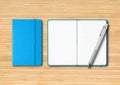 Blue closed and open lined notebooks with a pen on wooden background Royalty Free Stock Photo