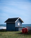 A blue closed wooden fishing hut next to some boats just by the beach in southern Sweden Royalty Free Stock Photo