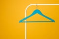 Blue clothes hanger on metal rack against yellow background Royalty Free Stock Photo