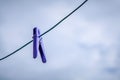 Blue clothespin hanging on a rope against a cloudy sky