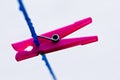 A blue clothing line with many raindrops at the string in front of a green background, with two pink and a blue peg after the rain