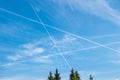 In a blue almost cloudless sky the contrails of airplanes cross Royalty Free Stock Photo