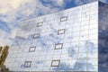 Blue clouds and trees are reflected in the glasses of windows of a modern building. Right view