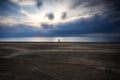 A blue and cloudy colored sunset, calm water and sandy beach.