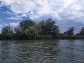 Blue cloudy sky over a wide river with a dense green forest.