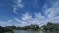 Blue cloudy sky over a wide river with a dense green forest.