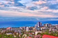 Blue coast of Black Sea in Sochi city with residential houses and recreation areas under summer cloudy sky