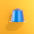 Blue coffee capsule floating on a vibrant yellow background Royalty Free Stock Photo