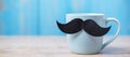 Blue coffee cup with Black mustache on wood table background in the morning. Father, International men day, Prostate Cancer