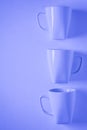 3 blue coffee mugs on blue background in a vertical row with empty copyspace