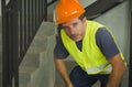 Blue collar job lifestyle. Portrait of tired and exhausted construction worker in helmet and vest at building site taking a breath Royalty Free Stock Photo