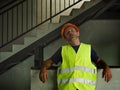 Blue collar job lifestyle. Portrait of young attractive and exhausted construction worker in helmet and vest at building site Royalty Free Stock Photo