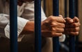 A blue collar man wearing white shirt and brown slacks behind the iron fence, hand holding iron fence with a sense of hopelessness