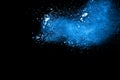 Blue color powder explosion cloud on black background.Closeup of Blue dust particles exhale on dark background