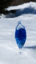 Blue color splashing out of a glass with egg on snow background Royalty Free Stock Photo