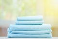 Blue colored bedding on a blurred background. Stack of folded new sheets on the table