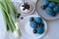 Blue colored Easter eggs on plates, spring flowers bouquet, sweet dessert on table, Easter holiday celebration dinner Royalty Free Stock Photo